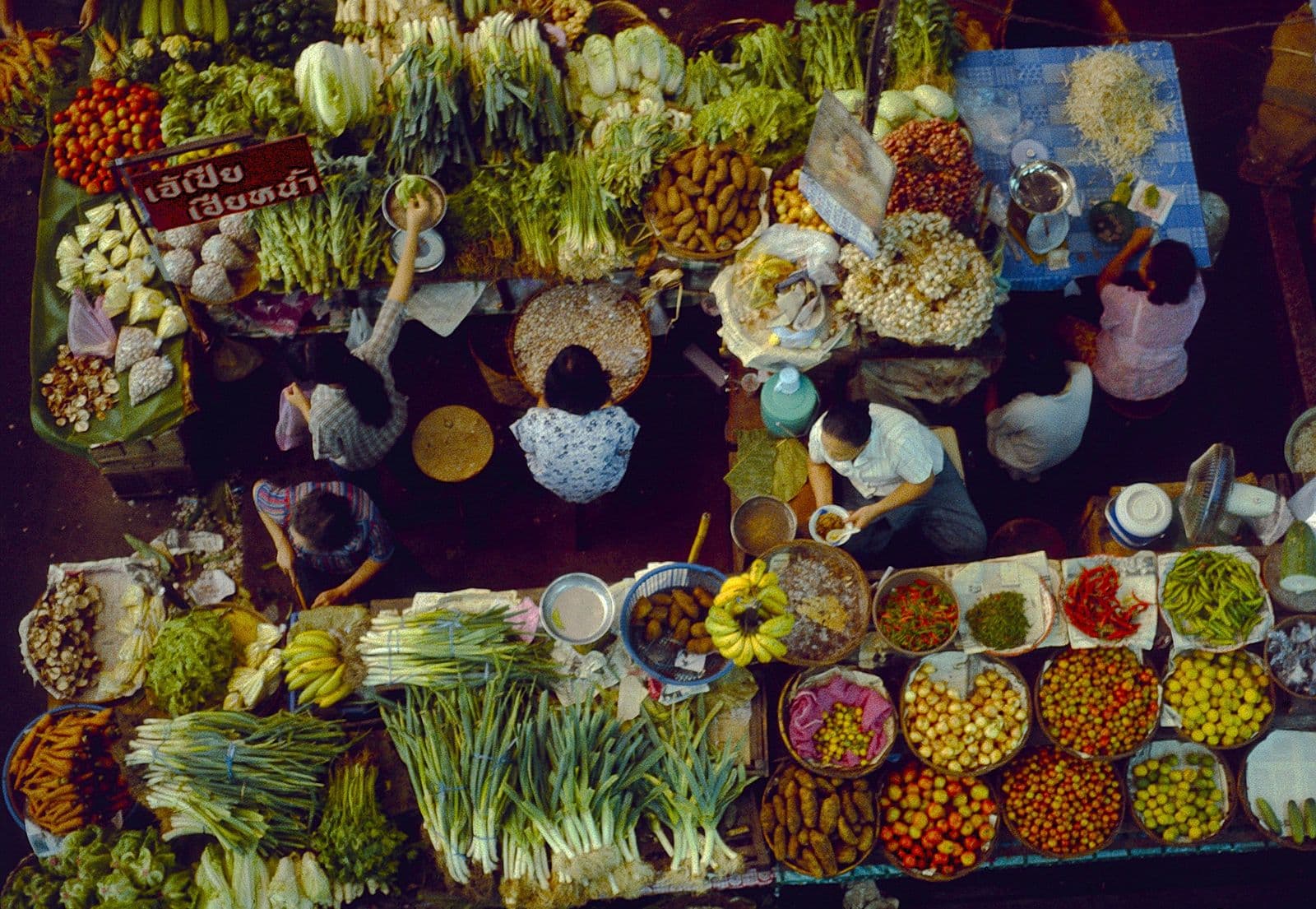 มุมมองจากด้านบนของตลาดผักผลไม้สดในเชียงใหม่ มีแผงเรียงรายและผู้คนเดินจับจ่าย
